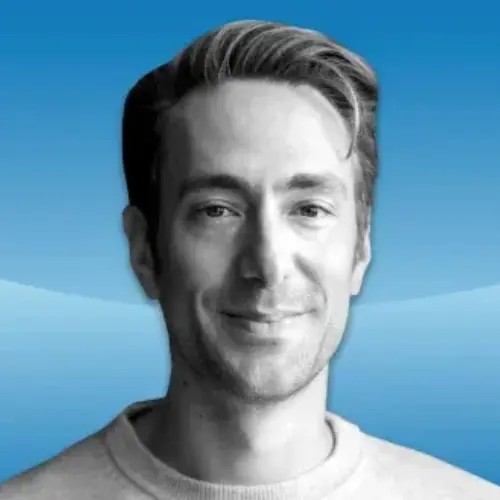 Black-and-white headshot of Andrew Wilkinson smiling, set against a blue background