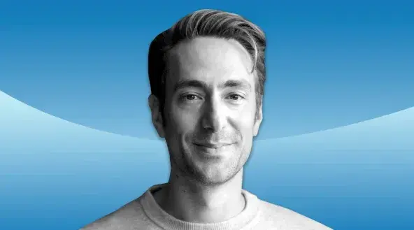 Black-and-white headshot of Andrew Wilkinson smiling, set against a blue background
