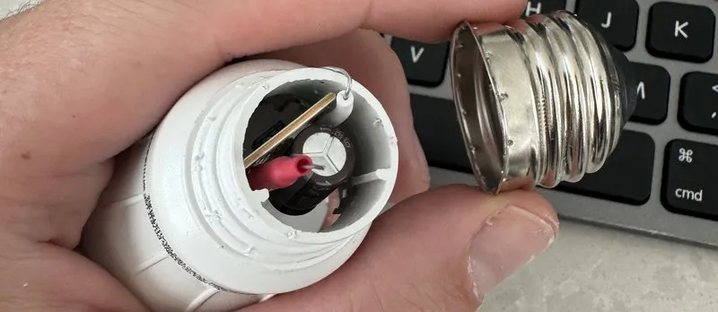 Opened LED bulb base revealing its internal power-supply electronics, with the metal screw base detached beside it